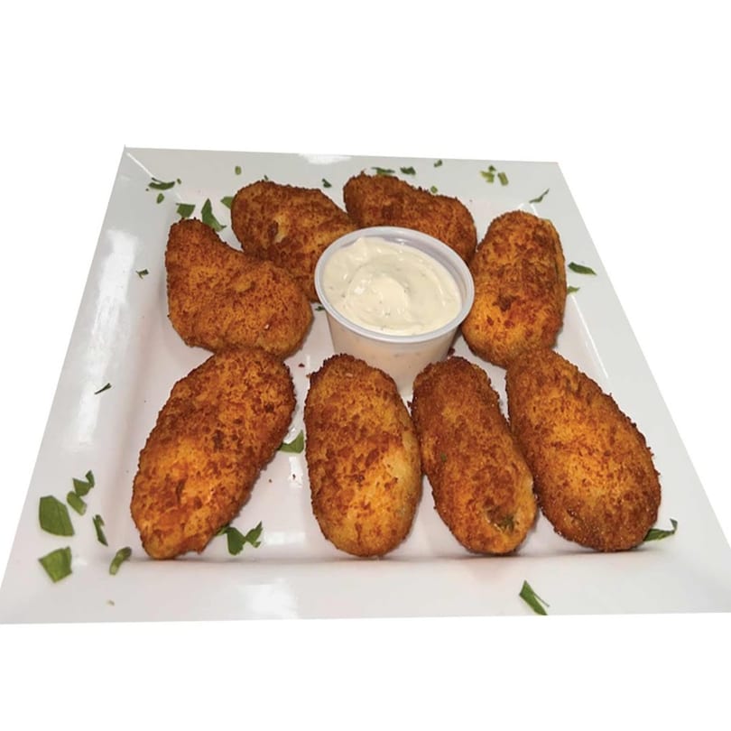 Eight golden-brown jalapeño poppers with a side of creamy dipping sauce on a white plate.