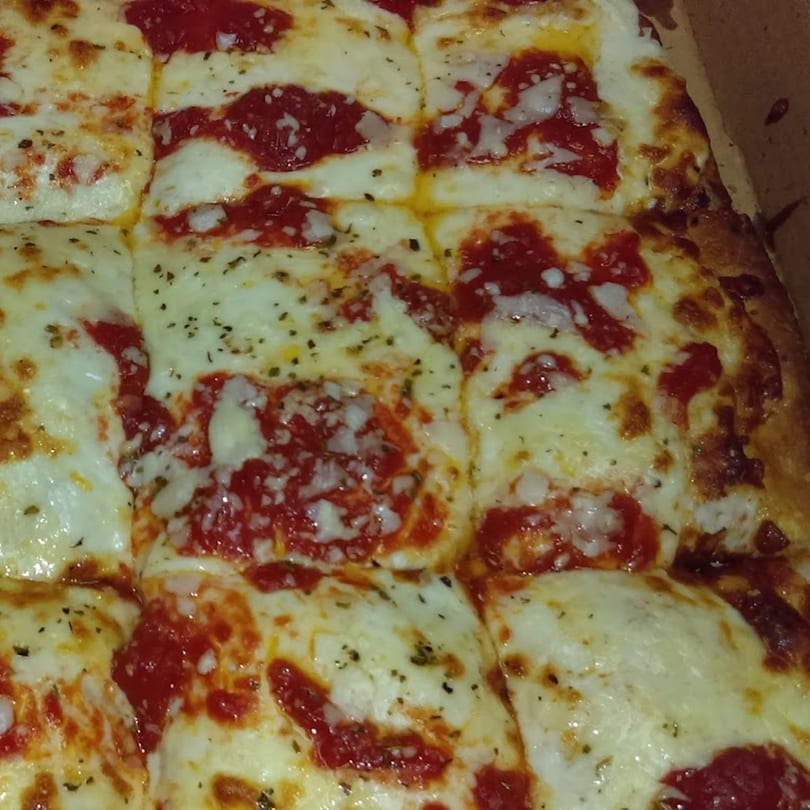 Close-up of a square-cut Two Brothers Topping's Pizza with melted cheese, red sauce, and herbs.